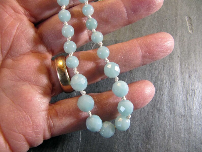 May include: A light blue gemstone necklace with faceted beads and a white cord.