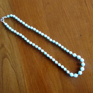 May include: A light blue beaded necklace with a silver clasp.
