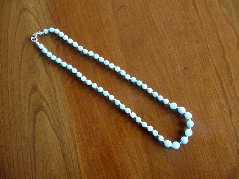 May include: A light blue beaded necklace with a silver clasp.