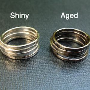 May include: Two silver rings, one shiny and one aged, with a hammered texture. The rings are stacked on top of each other.