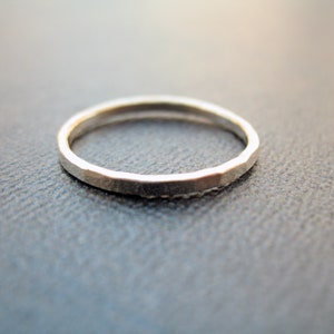 May include: A simple silver band ring with a hammered texture.