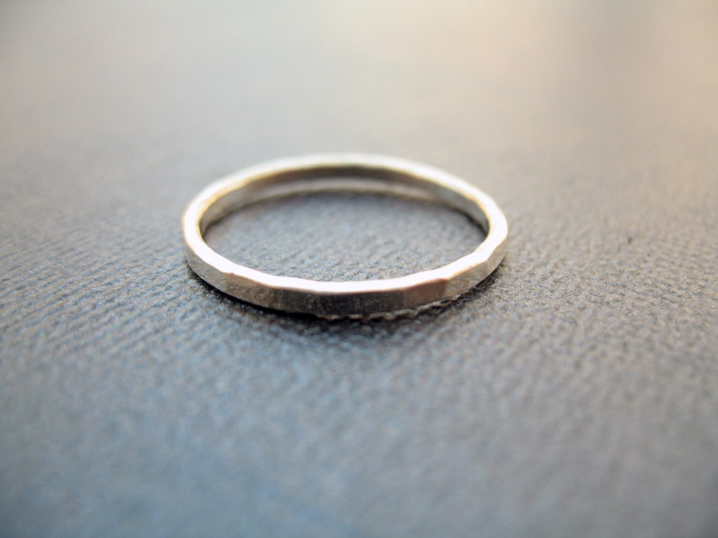 May include: A simple silver band ring with a hammered texture.