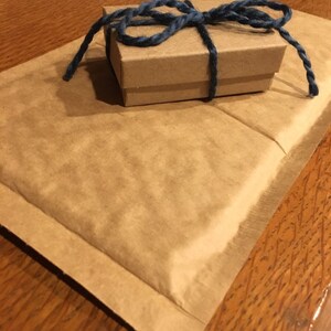 May include: A small brown box tied with a blue ribbon, sitting on a brown padded envelope.