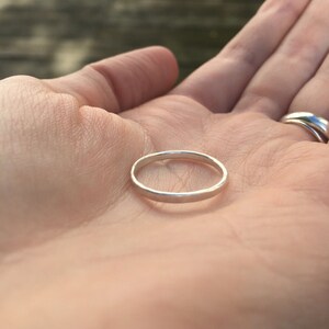 May include: A simple silver band ring, shown on a person's palm.