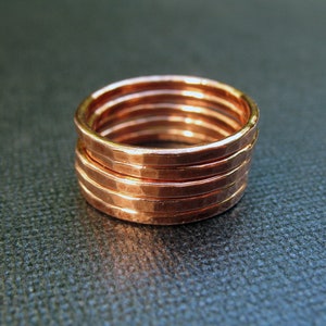 May include: Five stacked copper rings with a hammered texture. The rings are all the same size and are arranged in a stack.