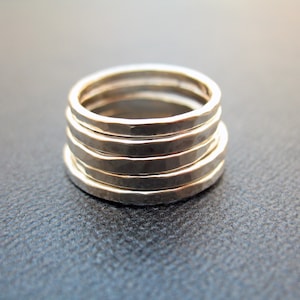 May include: Five silver rings stacked on top of each other. The rings are hammered and have a textured surface.