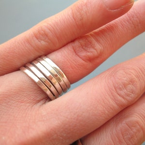 May include: A set of five silver hammered stacking rings. The rings are worn on a finger and are stacked on top of each other.