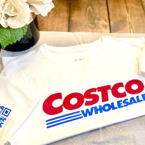 May include: White t-shirt with a red and blue Costco Wholesale logo and a blue and white QR code on the sleeve.