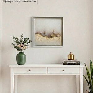 May include: A square framed abstract painting featuring a textured landscape with gold leaf accents, soft pink, and cream tones. The text MARCO NO INCLUIDO, FRAME NOT INCLUDED, and Ejemplo de presentación is visible in the upper left corner of the image.