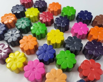 May include: A collection of flower-shaped crayons in various colors, including pink, yellow, green, orange, and purple. The crayons are arranged on a white surface, creating a vibrant and playful display. Each crayon is approximately 1 inch in diameter.