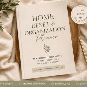 Op de afbeelding: Een beige planner getiteld Home Reset & Organization Planner met 18 essentiële checklists om je huis te resetten, op te ruimen en te organiseren. De kaft bevat een kleine bladillustratie en de tekst Calm Home, Clear Mind, More Time. Een gouden pen is inbegrepen.