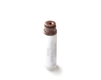 May include: A white tube of vegan lip balm with the words "Vegan Lip Balm" and "Clove" printed on the tube. The balm is a brown color.