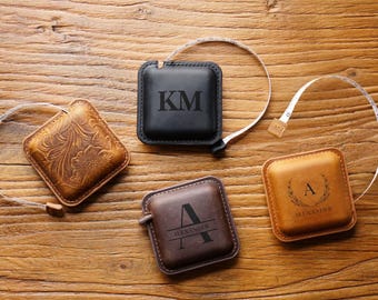 Peut inclure: Quatre rubans à mesurer en cuir personnalisés. L'un est noir avec les initiales "KM", l'autre est marron avec l'initiale "A" et le nom "Alexander", l'un est marron avec un motif floral et l'autre est marron avec les initiales "KM".
