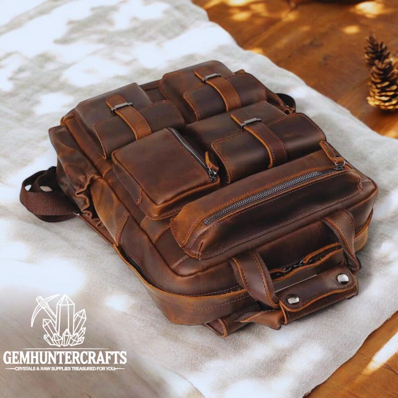 May include: A brown leather backpack with multiple pockets and buckles. The backpack has a distressed look and is made of high-quality leather.