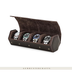 May include: A brown leather watch case with four watches inside. The case is open, revealing a soft, brown interior. The watches have silver bands and various colored faces. The case is rectangular with a curved top.