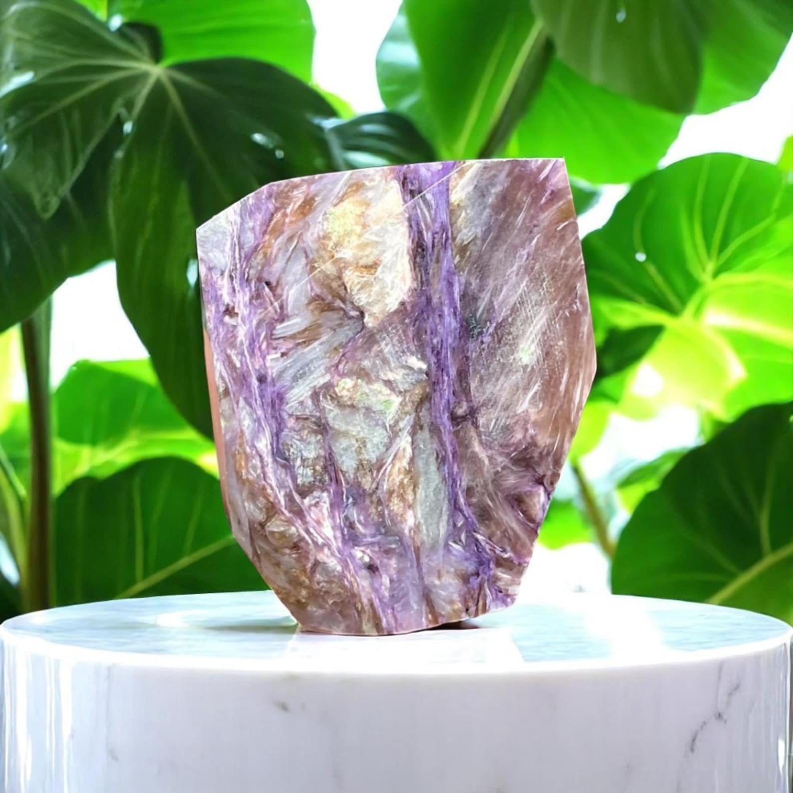 Large piece of charoite crystal with swirling purple and gold tones on a pedestal, representing spiritual transformation and strength for Scorpio.