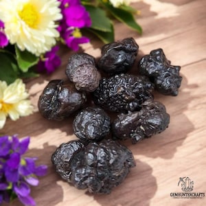 May include: A collection of eight black hematite nodules, also known as kidney ore, on a wooden surface. The nodules are irregularly shaped and have a rough, textured surface.