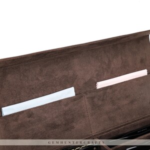 May include: A brown velvet eyeglass case with multiple compartments. The interior features a soft, plush texture and includes a light blue and a pink cleaning cloth. The case is designed to protect and organize eyewear.