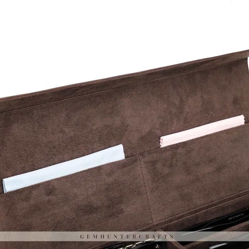 May include: A brown velvet eyeglass case with multiple compartments. The interior features a soft, plush texture and includes a light blue and a pink cleaning cloth. The case is designed to protect and organize eyewear.