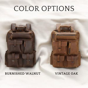 May include: Two leather backpacks in different colors. The backpack on the left is a dark brown color and is labeled "Burnished Walnut". The backpack on the right is a light brown color and is labeled "Vintage Oak".