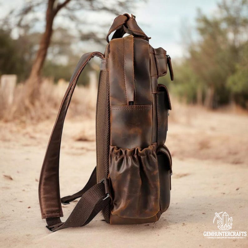 May include: A brown leather backpack with multiple pockets and a distressed look. The backpack has a large main compartment and a smaller front pocket. The straps are adjustable and the backpack is made of high-quality leather.