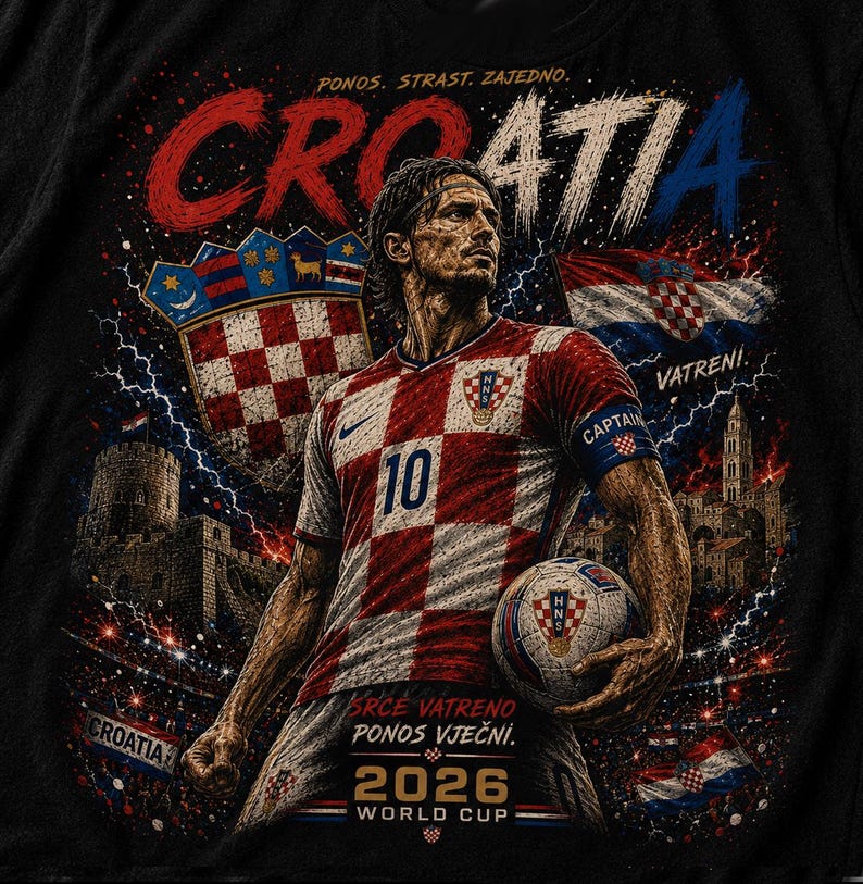 May include: A black t-shirt featuring a graphic of a football player in a red and white chequered jersey with the number 10, holding a football. The design includes the text CROATIA, 2026 WORLD CUP, and other Croatian phrases, with a shield, flag, and stadium background.