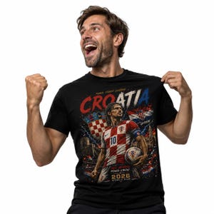 May include: A black t-shirt featuring a graphic print of a football player in a red and white chequered jersey with the number 10. The design includes the text "CROATIA", "PONOS, STRAST, ZAJEDNO", "VATRENI", "SRCE, VATRENO, PONOS VJEČNI!", and "2026 WORLD CUP".