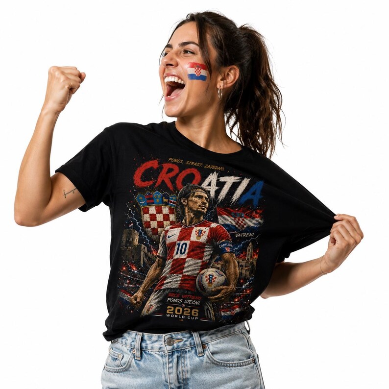 May include: A black t-shirt featuring a graphic print of a football player in a red and white chequered jersey with the number 10, the text CROATIA, the Croatian coat of arms, a football, and the text 2026 WORLD CUP printed on the front.