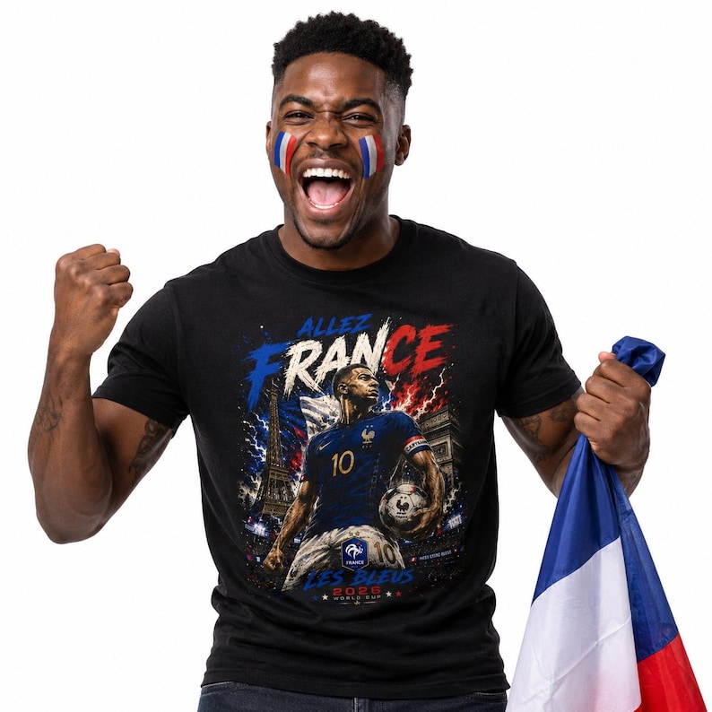 May include: A black t-shirt featuring a graphic print of a football player wearing a blue jersey with the number 10, holding a football. The design includes the text "ALLEZ FRANCE", "LES BLEUS", and "2026 WORLD CUP" with the Eiffel Tower.