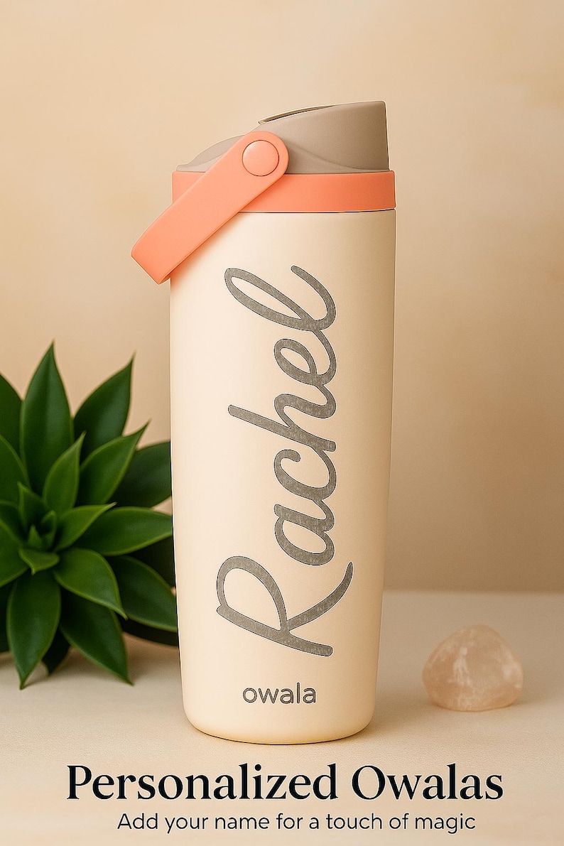 K&ouml;nnte beinhalten: Eine cremefarbene Owala-Trinkflasche mit grauem Deckel und pfirsichfarbenem Griff. Der Name "Rachel" ist in grauer Schrift aufgedruckt. Der Text "Personalisierte Owalas" und "F&uuml;gen Sie Ihren Namen f&uuml;r einen Hauch von Magie hinzu" stehen unten.