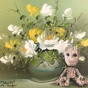 May include: A painting of a bouquet of white and yellow flowers in a clear vase with a small, green, wooden figurine sitting in front of the vase. The figurine has a large head with a wide smile and large eyes. The background is a muted green.