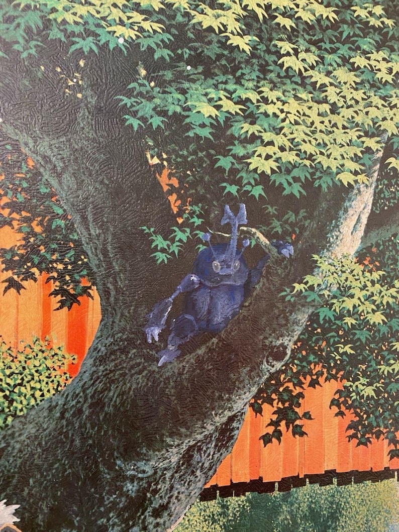 May include: A blue beetle with a long horn sits on a tree branch. The tree is in a garden setting with a red fence and green foliage.
