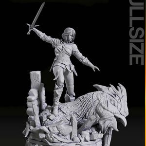 May include: A detailed figurine of a woman with a sword, standing atop a creature with a textured hide. The figure is set on a rocky base with wooden posts. The word "FULLSIZE" is printed vertically on the right side.