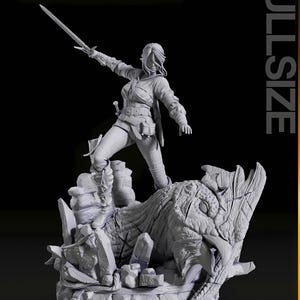 May include: A detailed gray figurine of a warrior woman holding a sword, standing atop a dragon-like creature. The figure is in a dynamic pose, with the sword raised. The base features rock formations and the word "FULLSIZE".