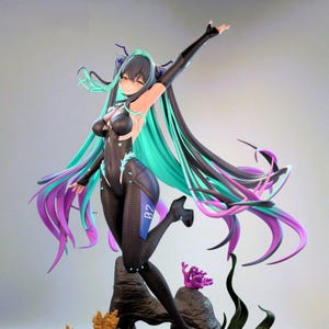 Puede incluir: Figura detallada de un personaje en una pose dinámica. La figura lleva un body negro con detalles azules y tiene un pelo largo y suelto en tonos turquesa, negro y morado. La figura posa sobre una base rocosa con detalles de coral y algas.