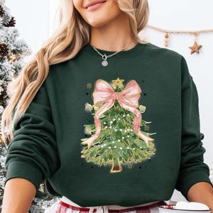 a woman wearing a green christmas sweater with a pink bow