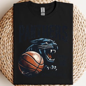 a black t - shirt with a panther holding a basketball