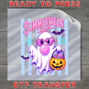 May include: A DTF transfer sheet featuring a white ghost wearing pink heart-shaped glasses and blowing a pink bubble. The ghost holds an orange jack-o'-lantern candy bucket. The text reads SUMMERWEEN, accompanied by purple bats and stars.