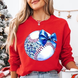 a woman wearing a red sweatshirt with a baseball on it