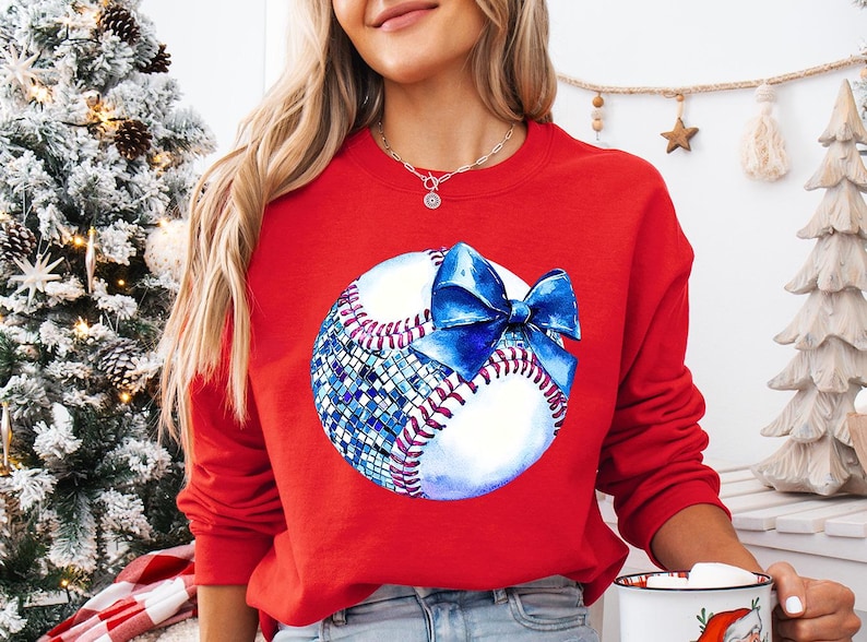 a woman wearing a red sweatshirt with a baseball on it