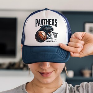 a woman holding up a hat with a panther on it