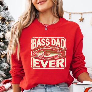 a woman wearing a red bass dad sweatshirt holding a cup of coffee