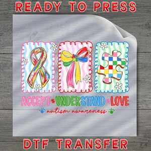 May include: A DTF transfer with three colorful designs: a rainbow ribbon, a bow, and a puzzle piece. The words "ACCEPT * UNDERSTAND * LOVE" and "autism awareness" are also printed on the transfer.