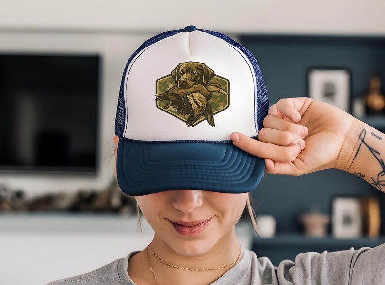 A woman is holding up a blue and white baseball cap with a hunting dog on it, smiling at the camera.