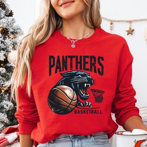 a woman in a red sweatshirt holding a basketball mug