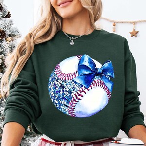 a woman wearing a green sweatshirt with a baseball on it
