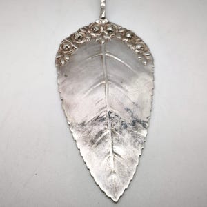 Peut inclure: Une pelle &agrave; g&acirc;teau argent&eacute;e avec une lame en forme de feuille. Le bord de la lame est festonn&eacute;. La poign&eacute;e est surmont&eacute;e d'un motif floral d&eacute;coratif. Le serveur est en m&eacute;tal et a une finition brillante.