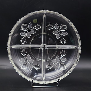 Puede incluir: Un plato de servir de vidrio transparente con cuatro secciones, cada una decorada con un diseño floral. El plato es perfecto para servir aperitivos, aperitivos o postres.