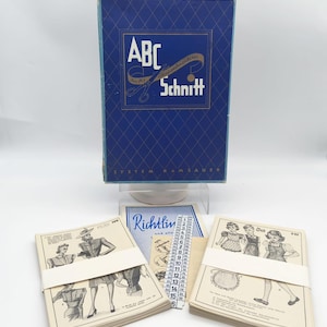 May include: A vintage sewing pattern set. The blue box has the text "ABC Schnitt". The set includes pattern booklets, a measuring tape, and other sewing materials. The booklets show illustrations of clothing designs.