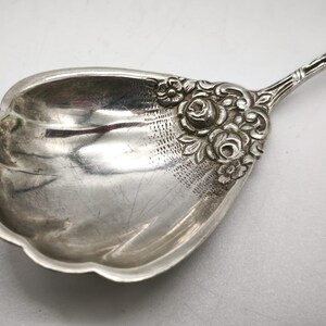 Peut inclure: Une cuill&egrave;re de service en argent avec un motif floral d&eacute;coratif. Le bol de la cuill&egrave;re a un bord festonn&eacute; et est orn&eacute; de d&eacute;tails grav&eacute;s. La poign&eacute;e pr&eacute;sente un motif floral d&eacute;taill&eacute;, ajoutant &agrave; son aspect &eacute;l&eacute;gant. La cuill&egrave;re est probablement vintage.